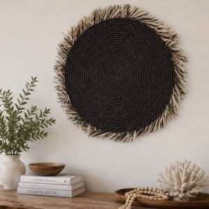 handmade round seagrass wall art with black center and fringe edging in black and neutral tones